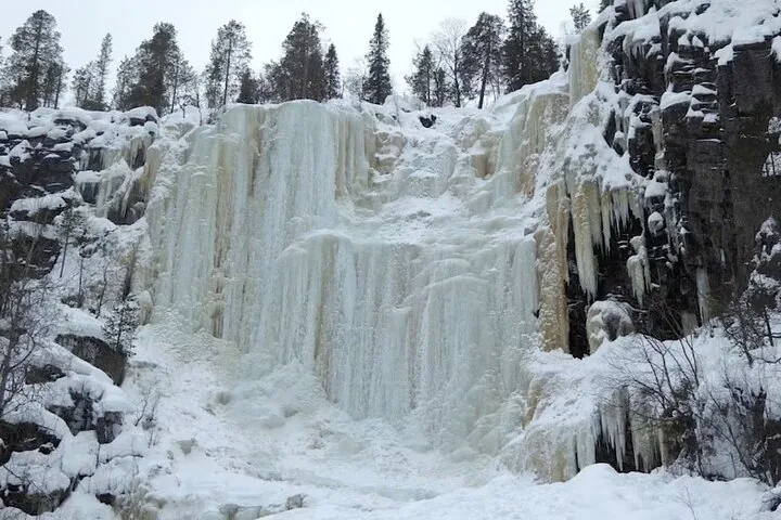 A towering wall of frozen waterfall ice on the cliffs of Korouoma Canyon
